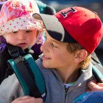 closeup teen wearing red cap carrying child with pink hat