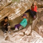 Three young girls sitting in a rock crevice.
