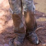 A person wearing camouflage pants standing in mud.