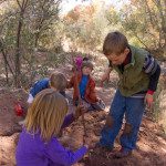 A group of children playing in the dirt on a trail.