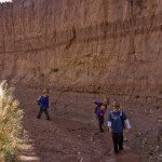 A group of kids walking through a rocky area near a cliff.