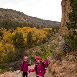 Two girls in pink jackets standing on a rocky trail.