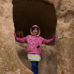 A girl in a pink jacket standing in a rock hole.
