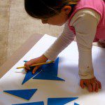 a little girl arranging blue parts on a paper