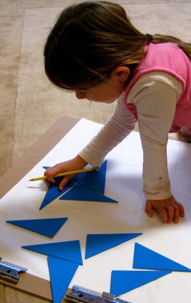 a little girl arranging blue parts on a paper