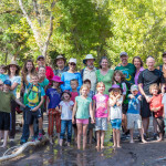 group photo of children and teachers outdoors in the stream