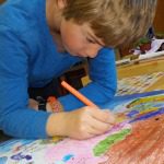 child coloring a drawing with colored pencils
