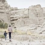 child and adult hiking with white canyon rock formation