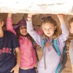 children holding onto a rock formation’s ceiling