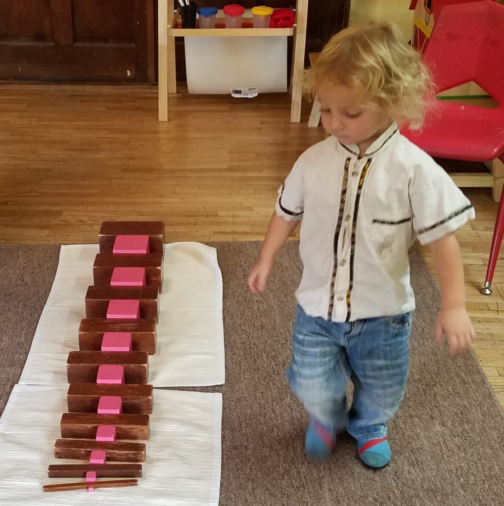 a cute little boy looking at the wooden blocks